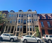 A silver car is parked in front of a building.